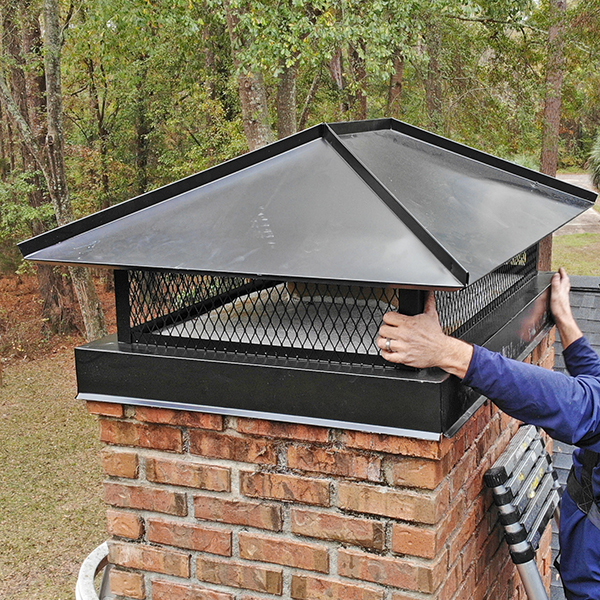 A stainless steel chimney cap securely fitted atop a brick chimney in Marshfield, MA, designed to prevent rain, debris, and animals from entering the flue.