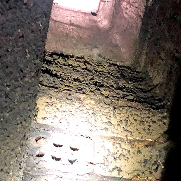 Close-up of heavy creosote buildup coating the interior walls of a chimney flue in Newton, MA a dangerous fire hazard requiring immediate professional cleaning.