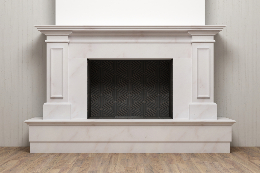 A white marble fireplace with decorative columns and a black geometric patterned firebox, set against a light-colored wall and wood floor—perfectly complementing expert chimney restoration Norfolk and Plymouth County, MA.